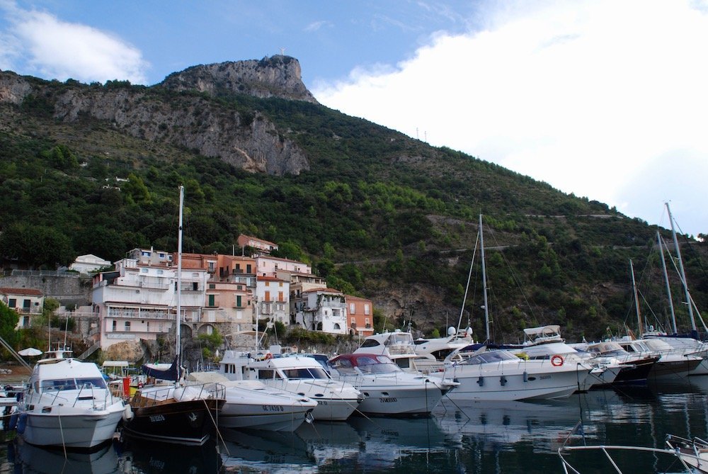 Porto di Maratea met vissersboten en kleurrijke huizen, op de achtergrond Monte San Biagio met het Christusbeeld Cristo Redentore.