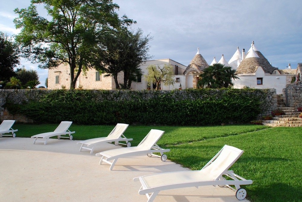 Ligbedden bij Masseria Cappuccini in Ostuni, met uitzicht op traditionele trulli en olijfgaarden in Puglia, Italië