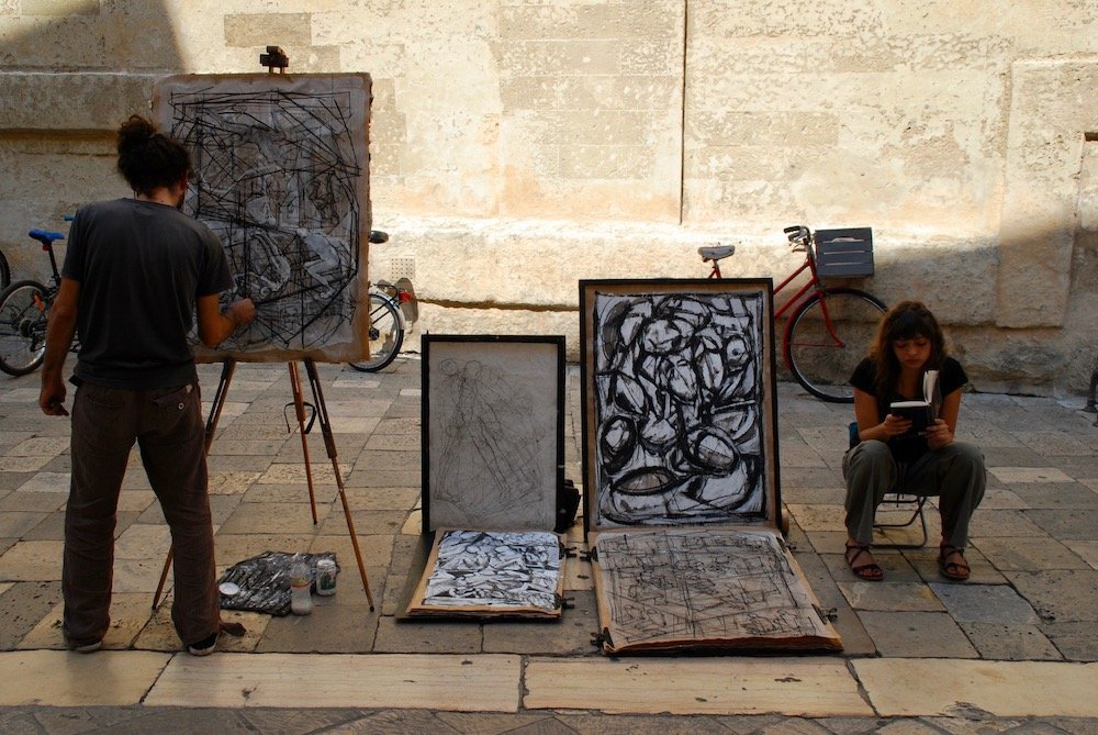 Kunstenaar schildert in de straten van Lecce, een creatieve bezienswaardigheid in het historische centrum