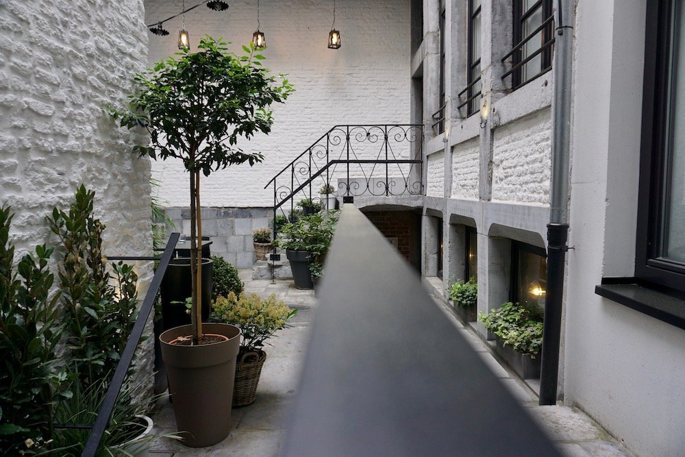 Binnenplaats van Hotel Neuvice in Luik met weelderig groen en een sfeervolle zithoek
