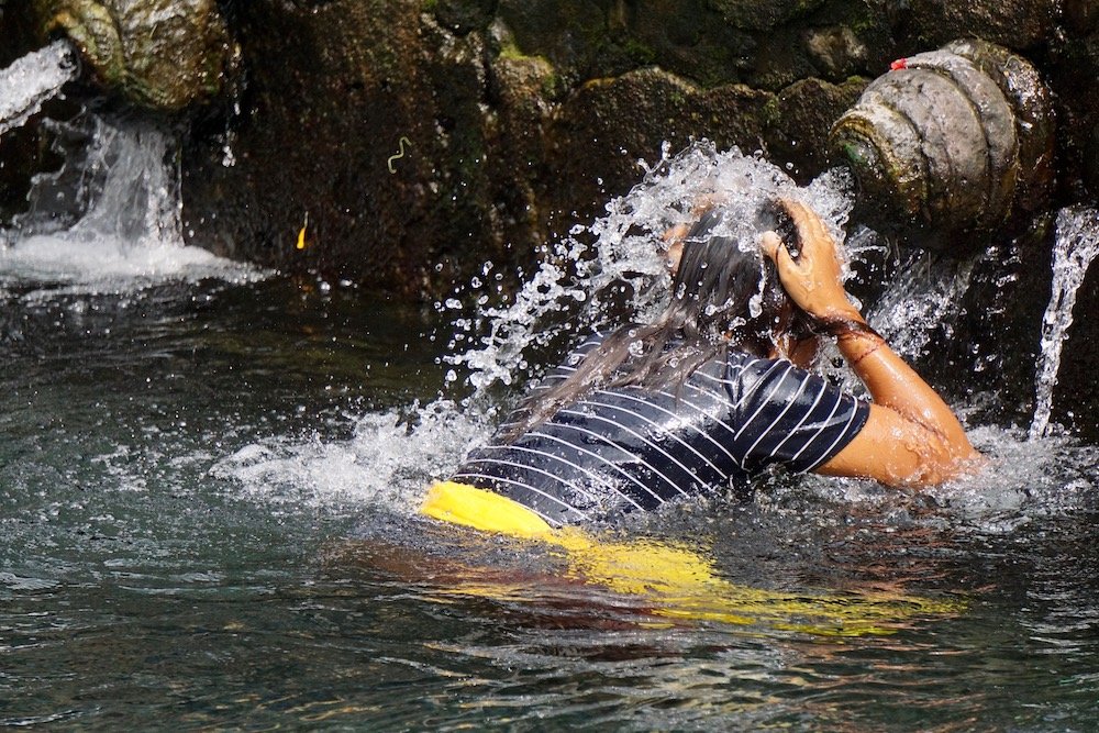 Vrouw tijdens het melukat-ritueel bij de Tirta Empul-tempel op Bali